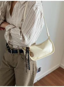 Detail of cream shoulder bag with woven knot and tennis racket pendant decoration