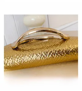 Macro detail of golden snakeskin embossed texture and metallic handle on handbag