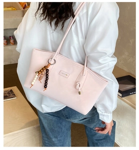 Detail of light pink tote bag with beaded charm accessory on model's shoulder