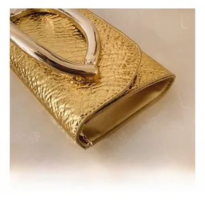 Macro shot of metallic gold python texture and polished U-shaped hardware hook on handbag