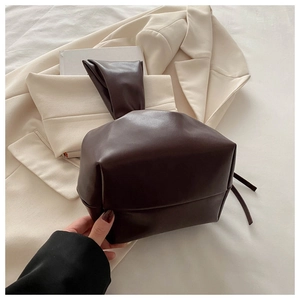 Detail of dark brown soft leather bucket bag with a unique single knotted handle