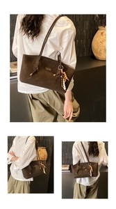 Detailed close-up of brown suede tote bag with wood bead tassel and metal brand logo