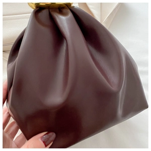 Detail of dark brown pleated leather bucket bag with elegant golden metal clasp closure