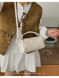 Close-up of elegant cream white cylinder bag with top handle and leather texture