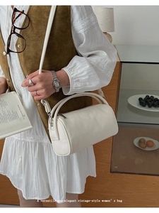 White cylinder crossbody bag with top handle and silver zipper in a retro style
