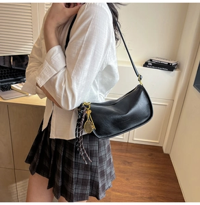Detail of black semi-circular crossbody bag with gold hardware and tennis racket charm