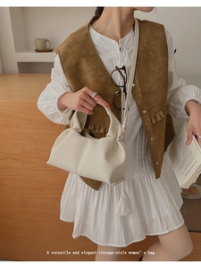 Sac à main chic en cuir crème avec plis élégants et fine bandoulière dans un cadre quotidien