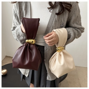 Detail of elegant gathered faux leather bucket bags with gold-tone hardware and drawstring