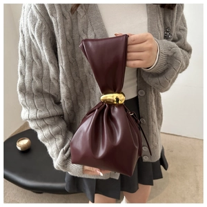 Close-up of a burgundy pleated cloud bag with a golden pebble metal buckle held by model