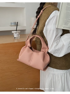 Sac bandoulière en cuir rose pâle porté par un mannequin dans un cadre intérieur