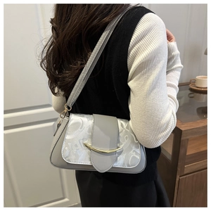 Detail der grauen Ledertasche mit weißem Jacquard-Flap und Gold-Schnalle an einem Model