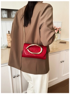 Red crocodile texture shoulder bag with gold ring buckle worn by a model in lifestyle setting