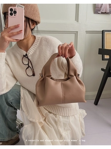 Détail d'un sac nuage plissé marron en cuir souple tenu par un mannequin en intérieur