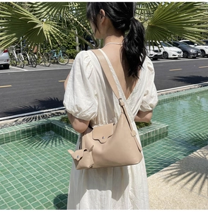 Detail of beige leather underarm bag featuring mini pouch accessory and metal buckle closure