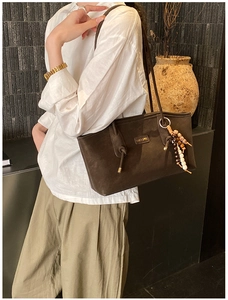Detail of a dark brown leather tote bag with colorful ethnic beaded tassel decoration