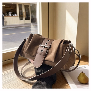 Gros plan du sac à bandoulière en suède marron avec boucle rétro et plis texturés