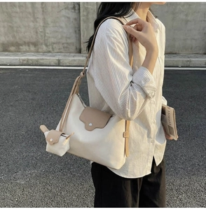 Detail view of the cream and khaki canvas tote with a mini coin purse pendant attachment
