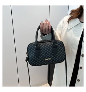 Detail of black geometric pattern handbag carried by a model in a long beige trench coat