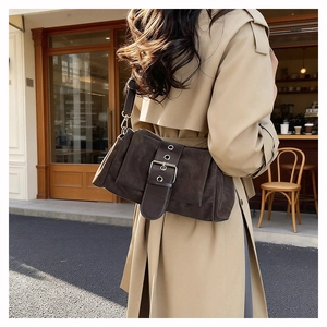 Sac sous le bras en daim marron avec boucle en métal montré dans un style de rue