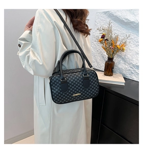 Detail of black crossbody bag with geometric patterns and golden logo on a side view model