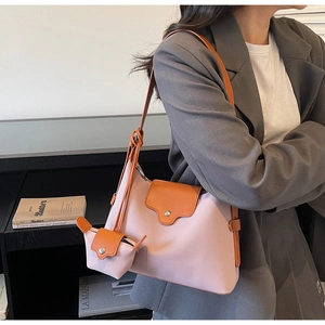 Detail view of pink canvas and caramel leather crossbody bag with a mini pouch charm