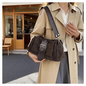 Gros plan d'un sac à bandoulière en daim marron foncé vintage avec une grande boucle en métal