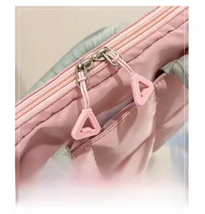 Detail of pink quilted laptop bag featuring smooth dual zippers and triangle pull tabs