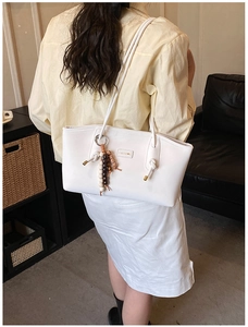 White leather tote bag detail with CHUUON logo and unique beaded ring charm attachment