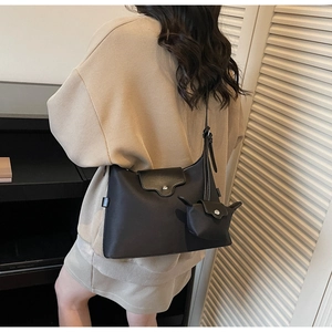 Detail view of black underarm bag with a cute ear-shaped charm on the side strap