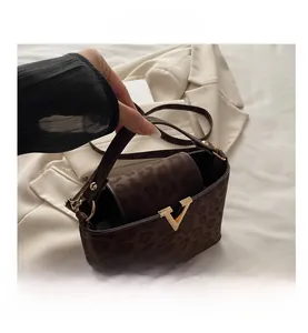 Close-up of leopard print handbag with gold V-shaped metal buckle and flap closure