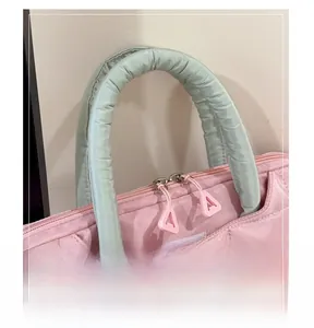 Detail of padded green handles and pink quilted fabric on large laptop tote bag