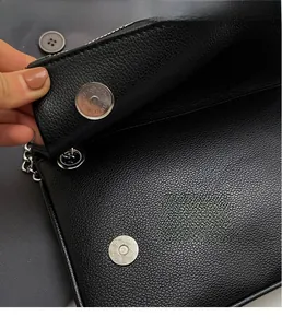 Dettaglio borsa in pelle nera martellata con chiusura magnetica argento e catena metallica