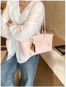 Detail of light pink tote bag with brand logo and bohemian beaded tassel accessory