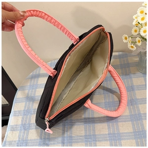 Interior view of black quilted laptop bag featuring pink handles and multiple compartments
