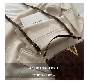 Detail of adjustable leather strap and golden V logo on leopard print crossbody bag