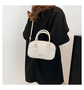 Detail of cream crossbody bag with brown geometric pattern and gold-tone hardware