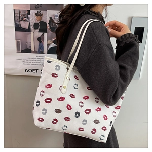 Close-up of white tote bag with colorful lipstick print patterns and slim handle
