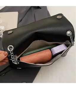 Dettaglio interno della borsa in pelle nera con catena e spazio per oggetti quotidiani