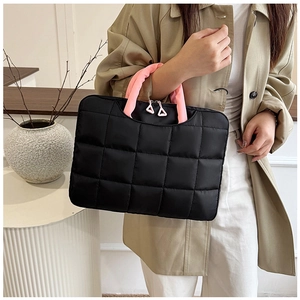 Detail of black quilted laptop bag featuring pink handles and triangle zipper pull