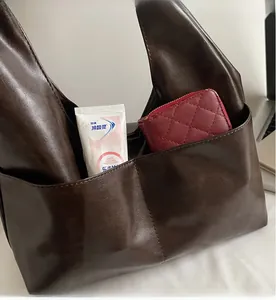 Detail of dark brown leather tote bag showing a functional front pocket with essentials