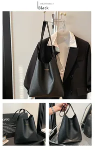 Detail of black leather tote bag featuring gold fashion logo and textured matte finish