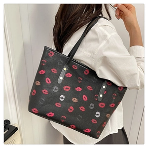 Detail of black tote bag featuring red lip prints with a leather strap and rivet decor