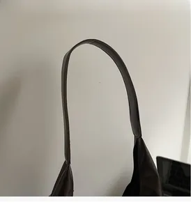 Detail of the durable dark brown leather handle and stitching on this commute tote bag