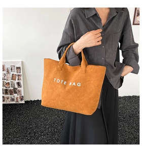 Close-up of caramel tote bag with white TOTE BAG text print in a modern setting