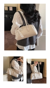 Detail view of cream Boston bag with leather texture and white lace bow accessory