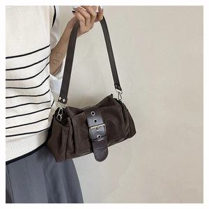 Détail d'un sac bandoulière vintage marron foncé avec une grande boucle en métal ajouré