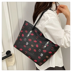 Close-up of black tote bag with colorful lipstick prints on textured leather