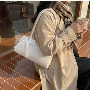 Detail view of cream Boston bag with lace bow charm and Free & Chic text print