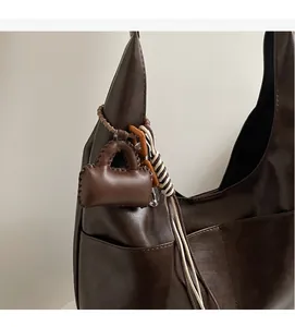 Close-up of matte dark brown faux leather shoulder bag with a mini pouch pendant detail
