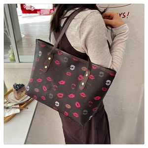 Brown tote bag with colorful lip prints shown on a model in a cozy cafe setting